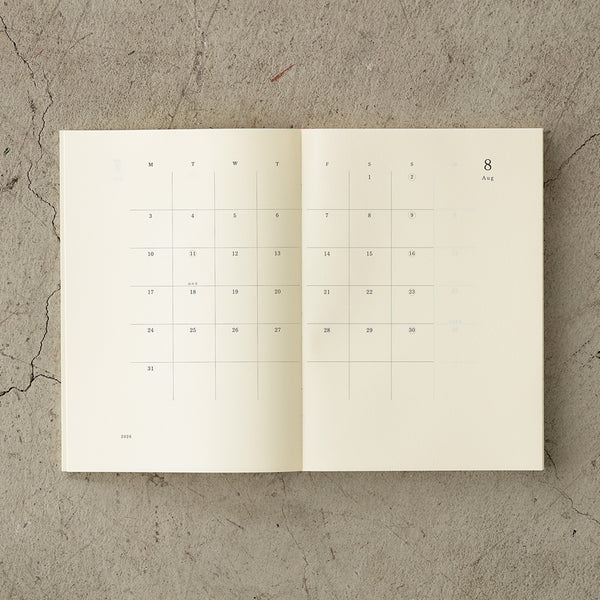 Load image into Gallery viewer, MD Notebook Diary (A5) Thin 2026 – A slim, thread-bound diary with a minimalist cream cover and glassine paper wrap, featuring monthly schedule pages, 5mm grid memo pages, and a bookmark string. Compact and lightweight, designed for portability and everyday use.