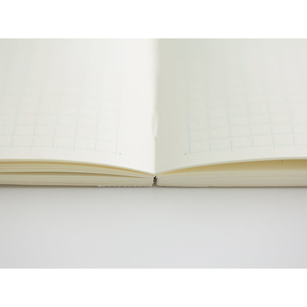 Load image into Gallery viewer, MD Notebook Diary (A5) Thin 2026 – A slim, thread-bound diary with a minimalist cream cover and glassine paper wrap, featuring monthly schedule pages, 5mm grid memo pages, and a bookmark string. Compact and lightweight, designed for portability and everyday use.