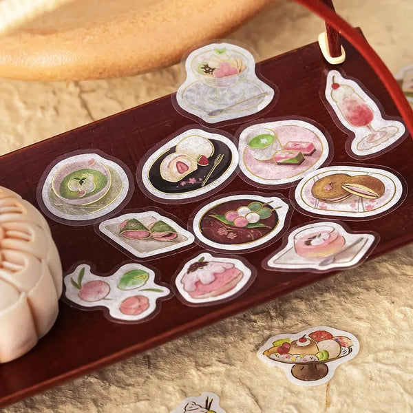 将图片加载到图库查看器，Pink-toned café flake stickers showing cakes, parfaits and delicate desserts with warm foil accents on washi paper.
