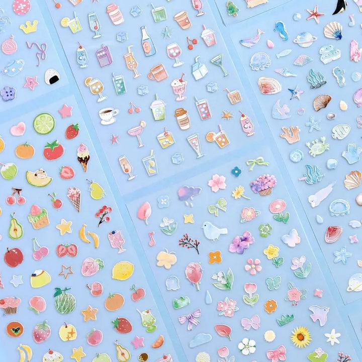Variety of BGM Seat Seal designs, including Colorful Fruits, Soft and Fluffy Drinks, Colors of Life, Sea and Cosmos, Animal Meets, and Bloom. Each sheet features unique PET stickers with playful, textured illustrations for journaling and decorative use.