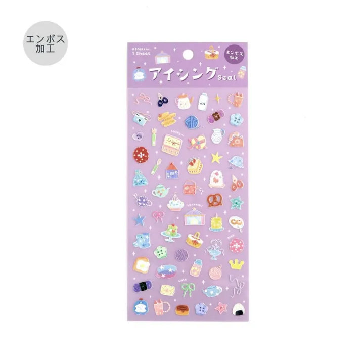 BGM Seat Seal – Colors of Life featuring a PET sticker sheet with pastel-toned icons of daily life: cameras, tea, yarn, sweets, and accessories, with a glossy embossed texture on a lavender background.