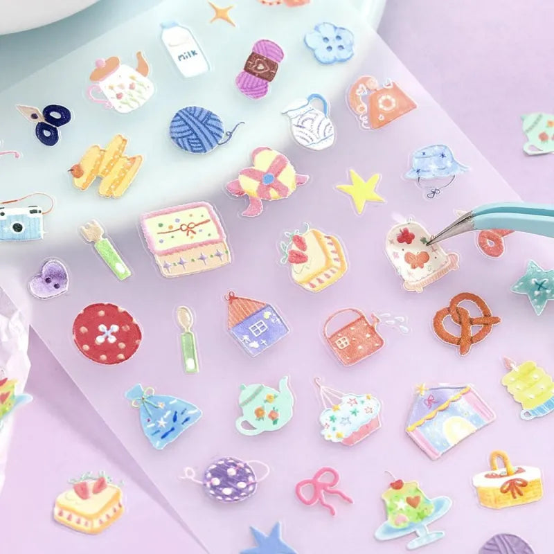 BGM Seat Seal – Colors of Life featuring a PET sticker sheet with pastel-toned icons of daily life: cameras, tea, yarn, sweets, and accessories, with a glossy embossed texture on a lavender background.