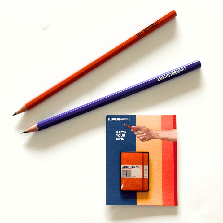 Leuchtturm1917 notebook pin in Pumpkin orange on its backing card, styled with pencils (not included)