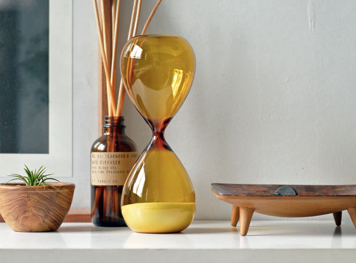 Hightide Hourglass L-Slim Amber – 15-minute tall slim glass timer with white sand and amber-toned body.