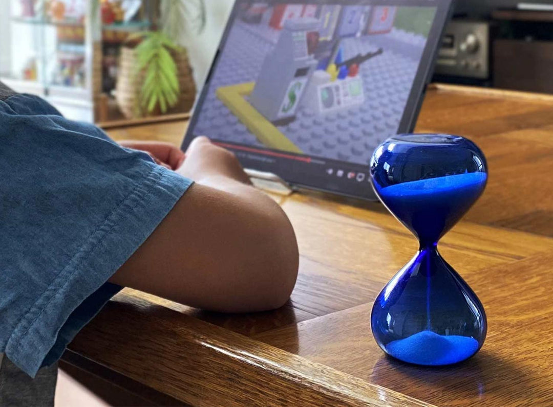 Hightide Hourglass M Blue – 5-minute glass sand timer with white sand in tranquil blue glass body.