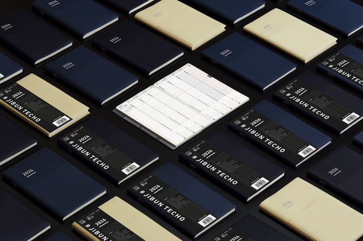 A compact B6 Mini Slim planner in matte black with an integrated pen holder. Inside, clean layouts on premium MIO PAPER include vertical weekly pages, monthly blocks, and reflection lists, designed for professional planning in a portable size.