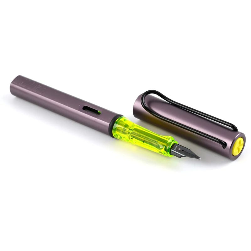 LAMY AL-star fountain pen in metallic aubergine with a translucent neon yellow grip, black steel nib, and metal clip. Includes a blue ink cartridge.
