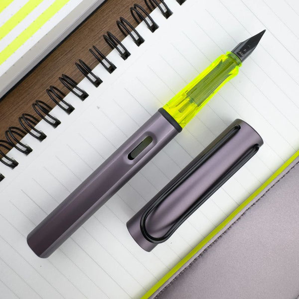 Load image into Gallery viewer, LAMY AL-star fountain pen in metallic aubergine with a translucent neon yellow grip, black steel nib, and metal clip. Includes a blue ink cartridge.
