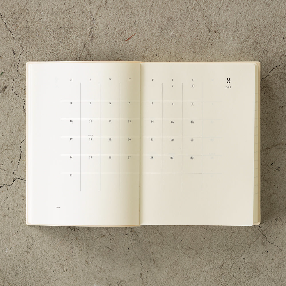 MD Notebook Diary (A5) 1 Day 1 Page 2026 with a minimalist PVC cover, year-stamped spine, and index tabs for each month. The diary is open to show a clean daily page layout on premium MD PAPER, ideal for journaling or planning.