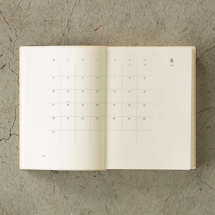 MD Notebook Diary (A5) 1 Day 1 Page 2026 with a minimalist PVC cover, year-stamped spine, and index tabs for each month. The diary is open to show a clean daily page layout on premium MD PAPER, ideal for journaling or planning.