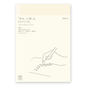  A5 MD Notebook Diary 2026 with a minimalist cream-toned glassine paper cover, thread-stitched binding, and a white bookmark string. The open spread displays a block-style monthly calendar on one side and lined memo pages on the other, printed on smooth MD PAPER designed for a premium writing experience.