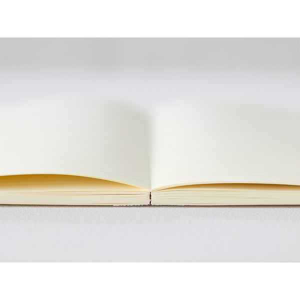 Load image into Gallery viewer, A5 MD Notebook Diary 2026 with a minimalist cream-toned glassine paper cover, thread-stitched binding, and a white bookmark string. The open spread displays a block-style monthly calendar on one side and lined memo pages on the other, printed on smooth MD PAPER designed for a premium writing experience.
