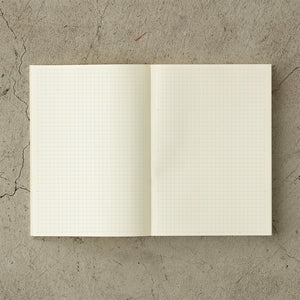 MD Notebook Diary (A5) Thin 2026 – A slim, thread-bound diary with a minimalist cream cover and glassine paper wrap, featuring monthly schedule pages, 5mm grid memo pages, and a bookmark string. Compact and lightweight, designed for portability and everyday use.