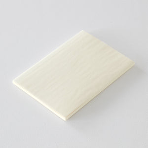 MD Notebook Diary (A5) Thin 2026 – A slim, thread-bound diary with a minimalist cream cover and glassine paper wrap, featuring monthly schedule pages, 5mm grid memo pages, and a bookmark string. Compact and lightweight, designed for portability and everyday use.