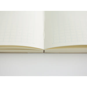 MD Notebook Diary (A5) Thin 2026 – A slim, thread-bound diary with a minimalist cream cover and glassine paper wrap, featuring monthly schedule pages, 5mm grid memo pages, and a bookmark string. Compact and lightweight, designed for portability and everyday use.