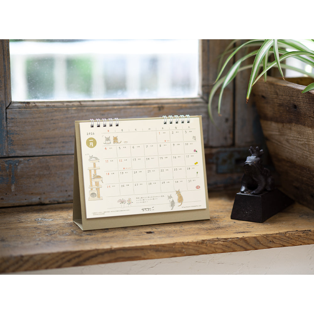 Midori Calendar Ring 2026 (M) – Cat, a freestanding desk calendar with soft, hand-drawn illustrations by Sayo Koizumi, depicting playful and cozy scenes of cats throughout the year.