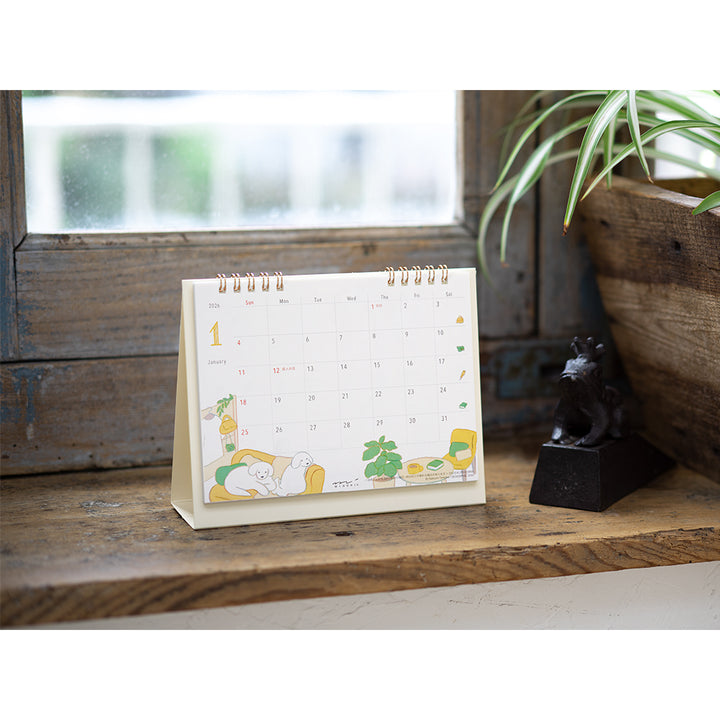 Midori Calendar Ring 2026 (M) – Dog, a compact desk calendar with colorful dog illustrations by Natsumi Teraoka, displayed upright to show its charming, hand-drawn monthly design.