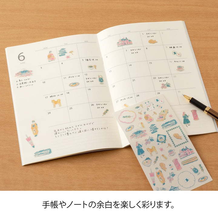 A sheet of Midori Sticker 2719 featuring delicate washi stickers of Japanese motifs, including cherry blossoms, Mount Fuji, seasonal foods, and traditional frame patterns in Yuuka Takamaru’s soft, pastel color palette.