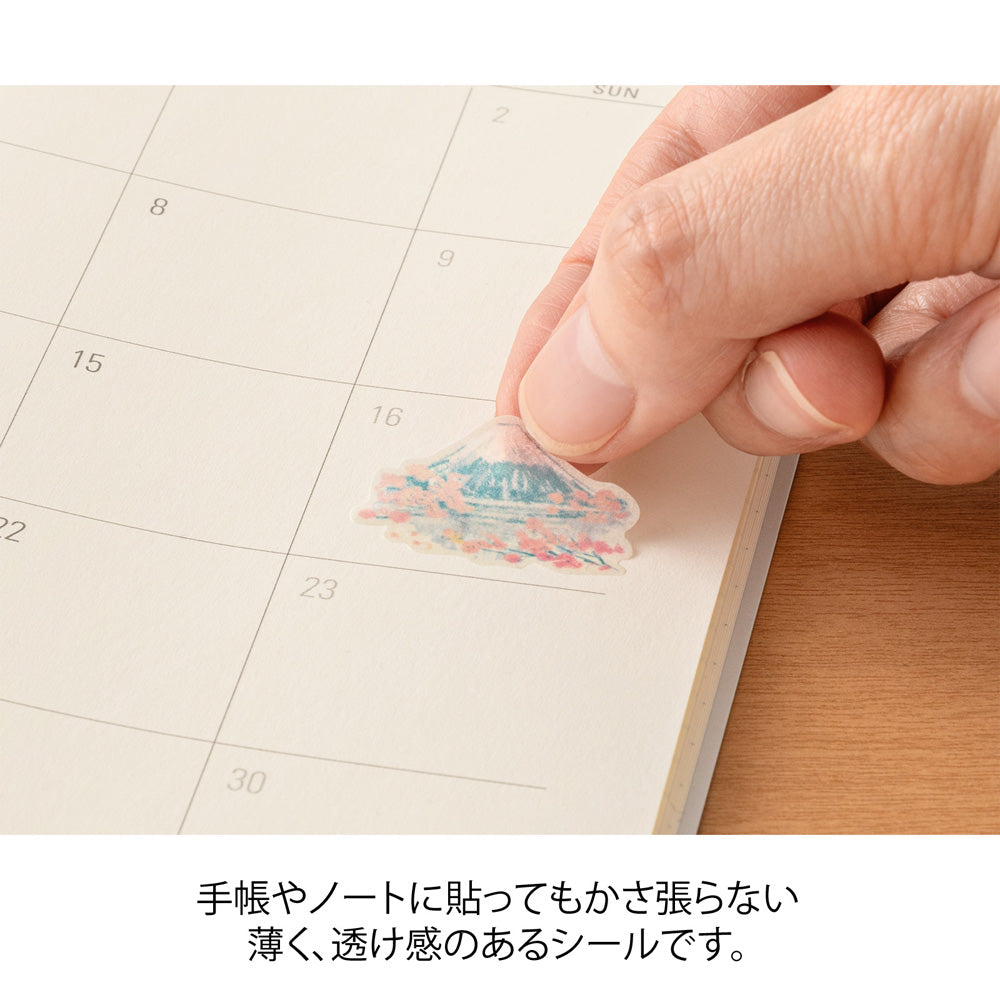 A sheet of Midori Sticker 2719 featuring delicate washi stickers of Japanese motifs, including cherry blossoms, Mount Fuji, seasonal foods, and traditional frame patterns in Yuuka Takamaru’s soft, pastel color palette.