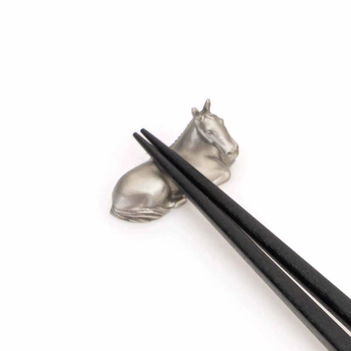 Elegant Royal Selangor 2026 Year of the Horse Chopsticks &amp; Rest Set, featuring polished wooden chopsticks with sculpted pewter horse accents and a pewter chopstick rest in a calm, reclining horse pose, symbolizing strength and grace.