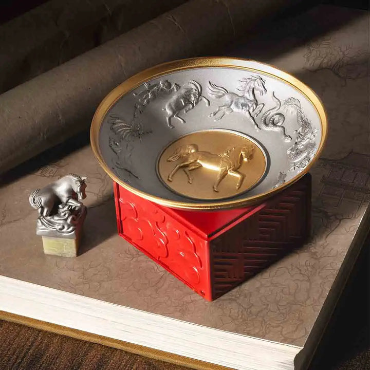 Royal Selangor 2026 Year of the Horse Wealth Bowl featuring a 24K gilt galloping horse at the center medallion, a zodiac frieze around the rim, and a crimson resin base detailed with waves, rocks, and clouds.
