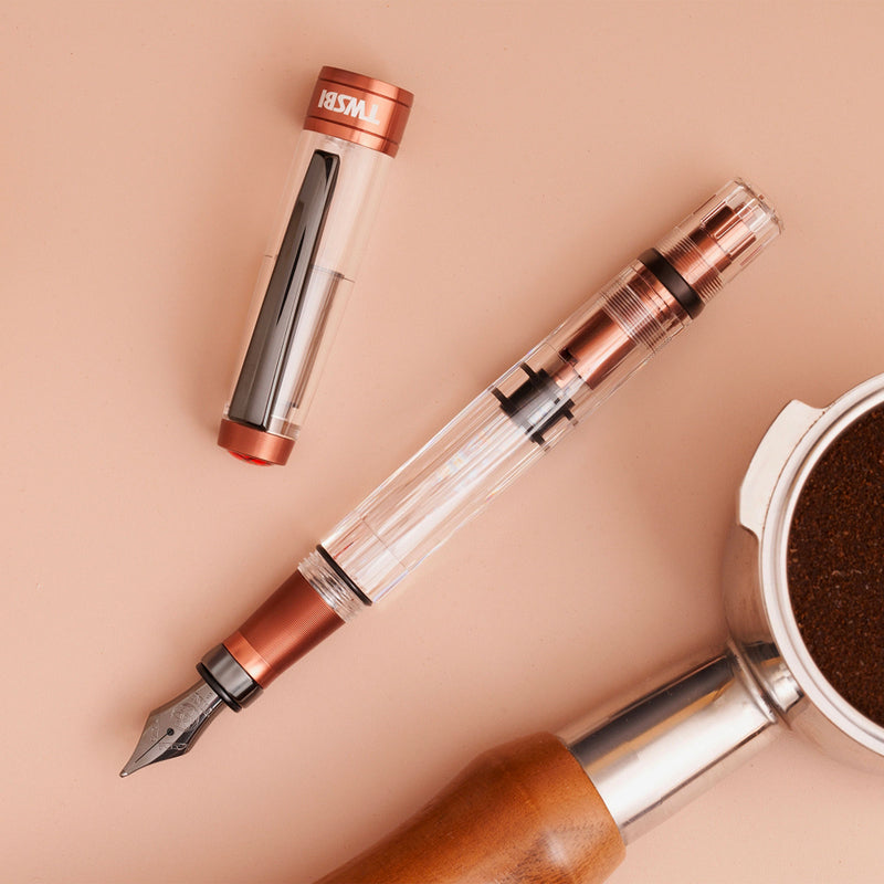 A TWSBI Diamond 580 AL R Affogato with Onyx fountain pen featuring a transparent barrel, copper-colored aluminum accents, and a black steel nib with matching trim, displayed in a clear presentation case.