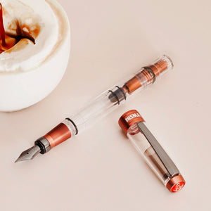 A TWSBI Diamond 580 AL R Affogato with Onyx fountain pen featuring a transparent barrel, copper-colored aluminum accents, and a black steel nib with matching trim, displayed in a clear presentation case.